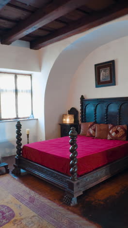 interior of the medieval bran castle in brasov, romania. approaching big wooden bed with red cover on. vertical video