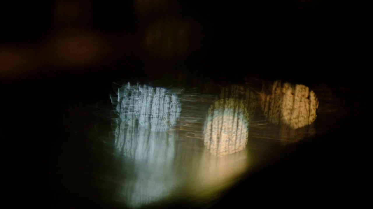 Out of focus car and traffic lights in the rain as seen through a wet window