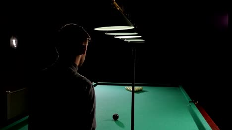 un joven guapo y exitoso jugando al billar ruso en un bar con amigos.