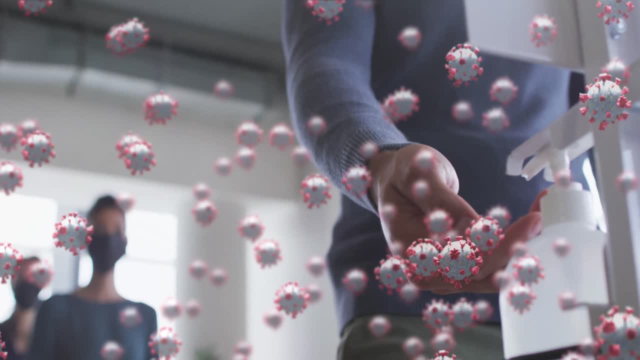 여러 개의 코로나19 세포가 사무실에서 손 소독제를 사용하는 마스크를 착용한 남자를 향해 떠다니고 있습니다.