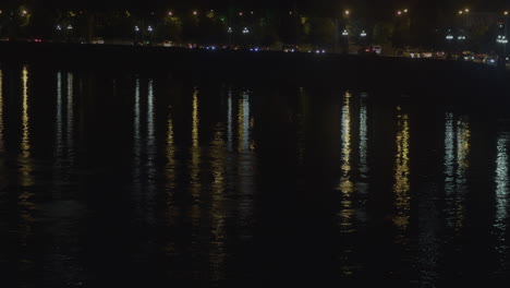 cars moving in the city at night, reflections on the river