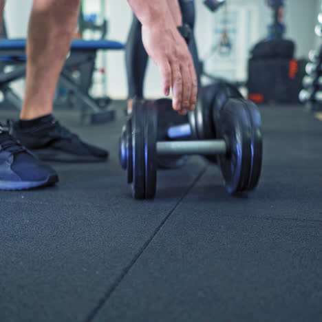 legs in trainers of a man and woman on the floor background of fitness center. dumbbells are put on the floor after training by a male and a female. close-up.