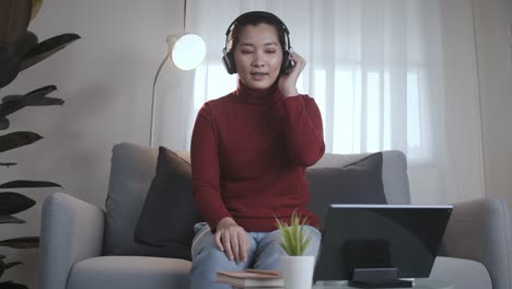 Mujer-Asiática-En-Camisa-Roja-Usando-Una-Tableta-Con-Auriculares-Para-Reunirse-En-Línea-En-Casa