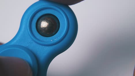 man-have-fun-playing-with-blue-spinner-on-light-background