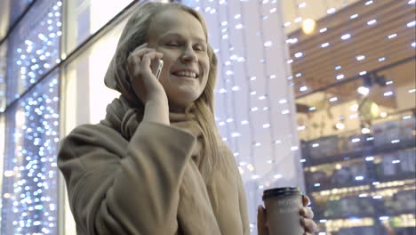 Woman-talking-on-phone-and-drinking-coffee-while-walking-in-street