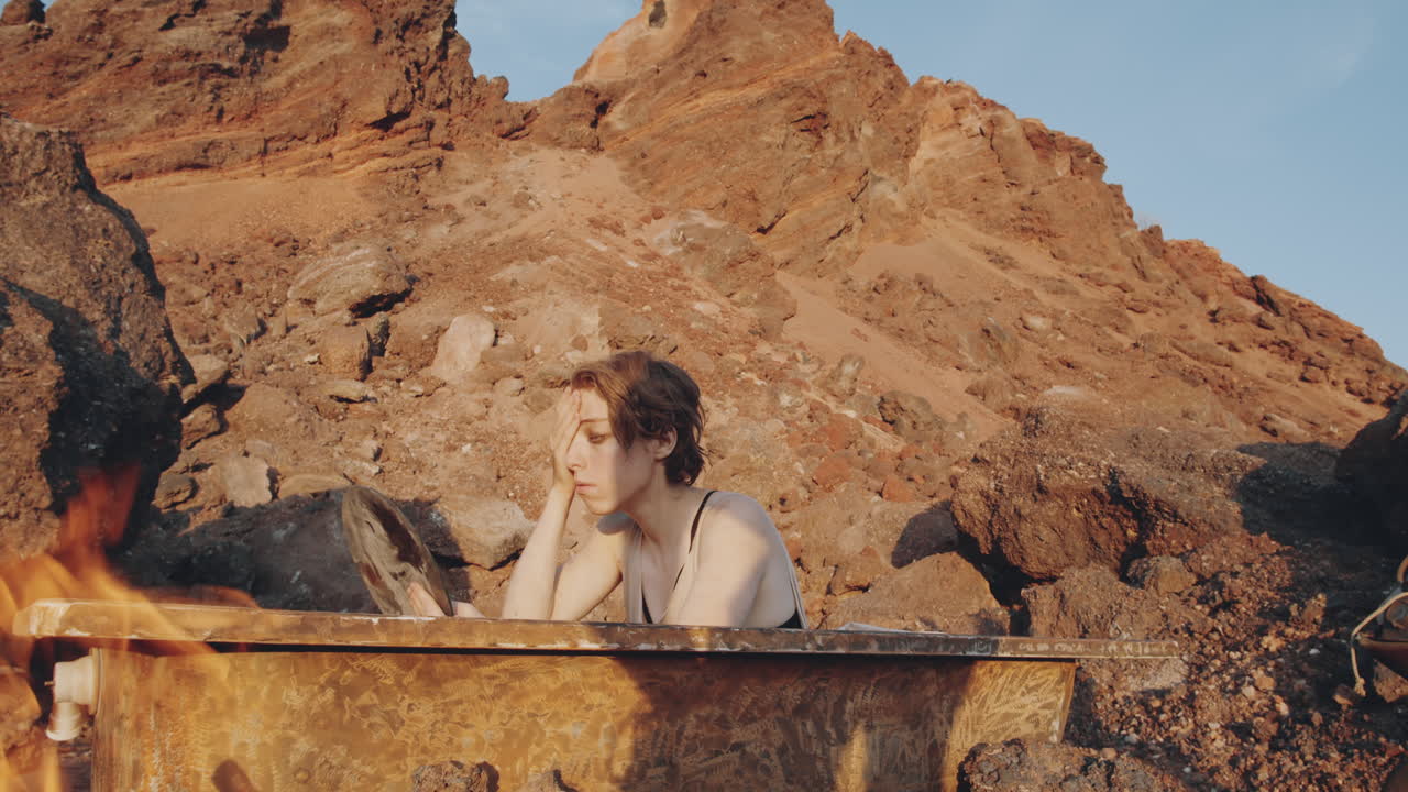 mujer sosteniendo un espejo y lavándose en el baño en un mundo post-apocalíptico