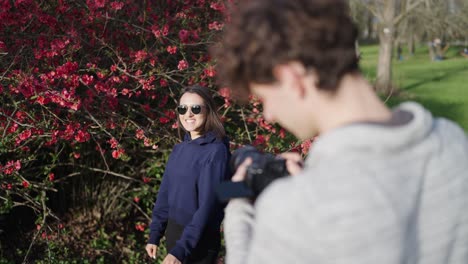 fotógrafo creativo y equipo de modelos femeninas cerca de un arbusto de quince chino en flor