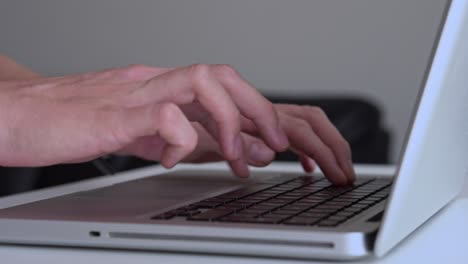 Close-up of male hands typing on laptop