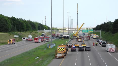 fire trucks, police cars, and a mobile crane clearing the debris at an oil tanker accident site in brampton, canada