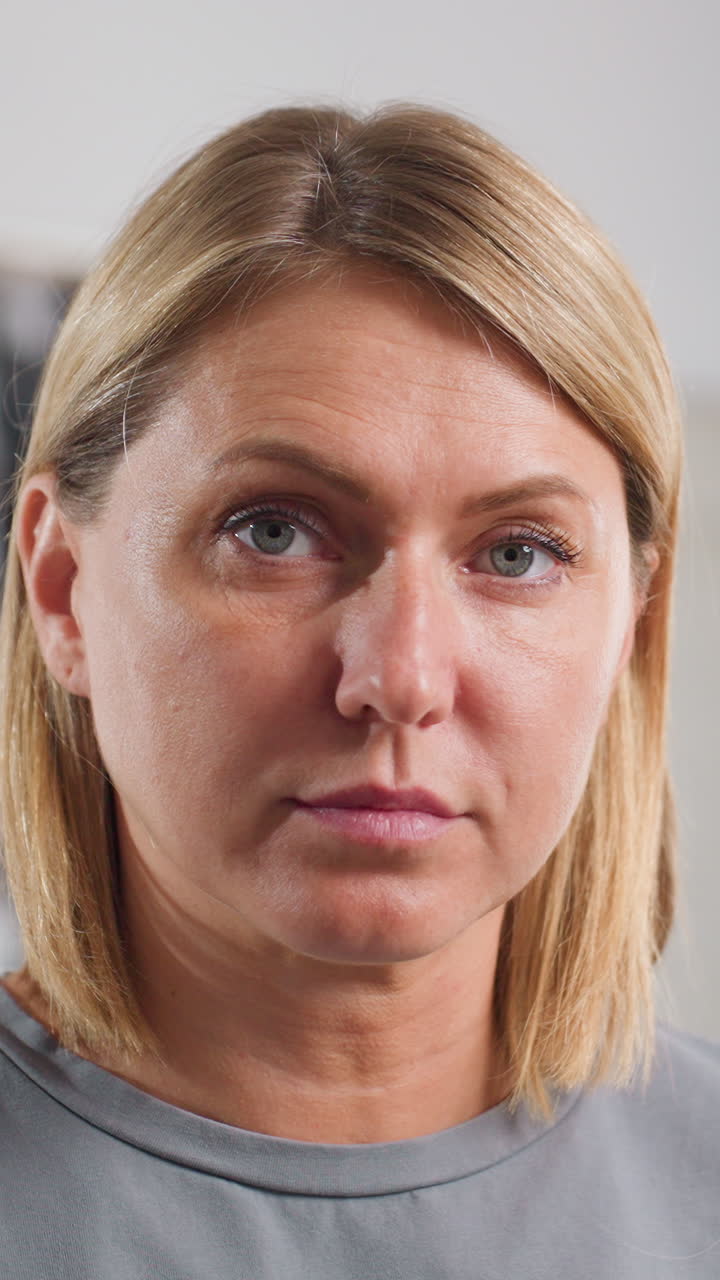 Primer plano de una mujer mirando hacia abajo en una clínica, expresión solemne, ligeras gotas en el pelo, escenas con iluminación suave de estudio que sugieren a una paciente esperando los resultados de las pruebas, a una profesora revisando apuntes o a una oficinista haciendo una pausa