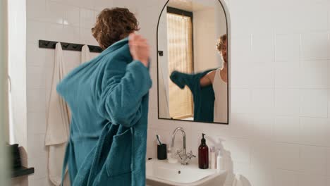 man getting dressed in a robe in the bathroom