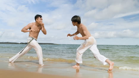 두 남자가 해변에서 카포에라를 춤추고 있다