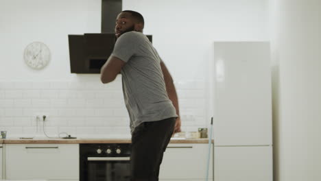 Joyful-black-man-clapping-hands-at-open-kitchen.-Happy-young-guy-dancing-at-home