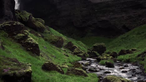 slowmotion shots of remote icelandic waterfall with man walking towards it