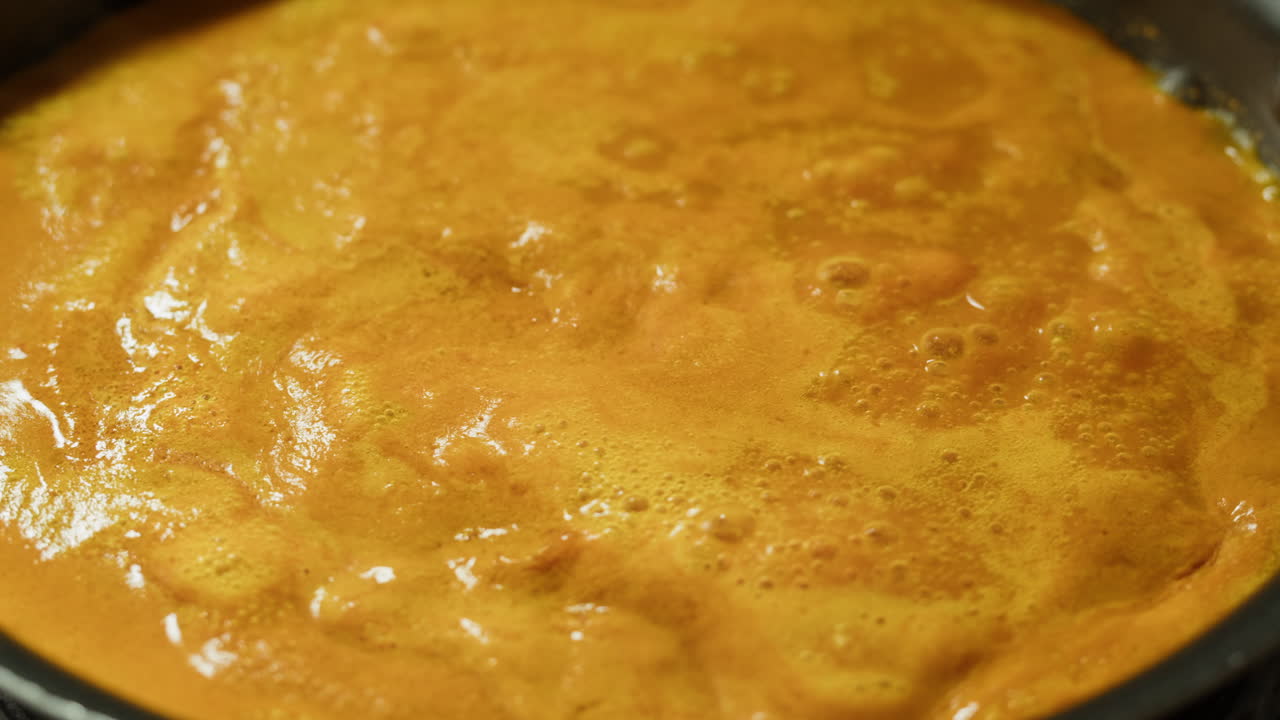 Yellow boiling sauce on pan close-up. Asian cuisine concept. Curry is a dish with a sauce seasoned with spices. Curries may contain fish, meat, poultry, or shellfish, either alone or in combination with vegetables. Others are vegetarian.