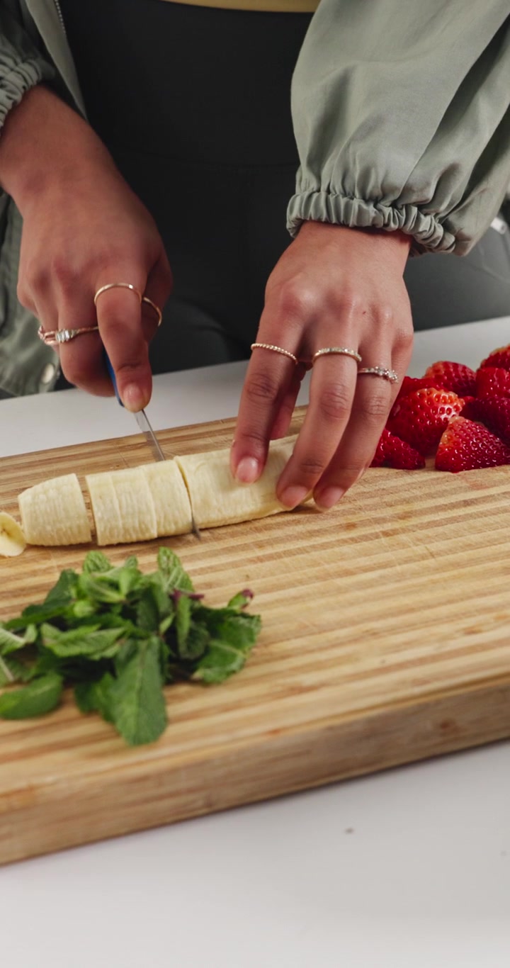Persona che affetta una banana fresca su un tagliere di legno