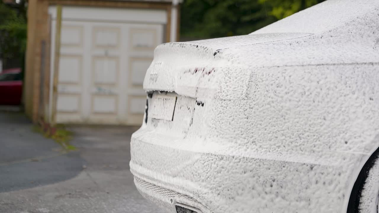 Schiuma neve bianca sul posteriore di un'auto nera