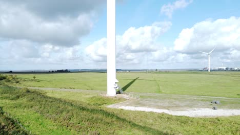 aerial view flying around renewable energy wind farm wind turbines spinning on british countryside low to high ascending shot