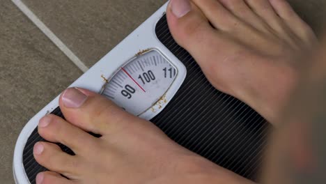 Close-up-slow-motion-shot-of-feet-stepping-onto-bathroom-scales-weight-measurements-body-human-foot-gym-mass-weight-loss-fitness-4K