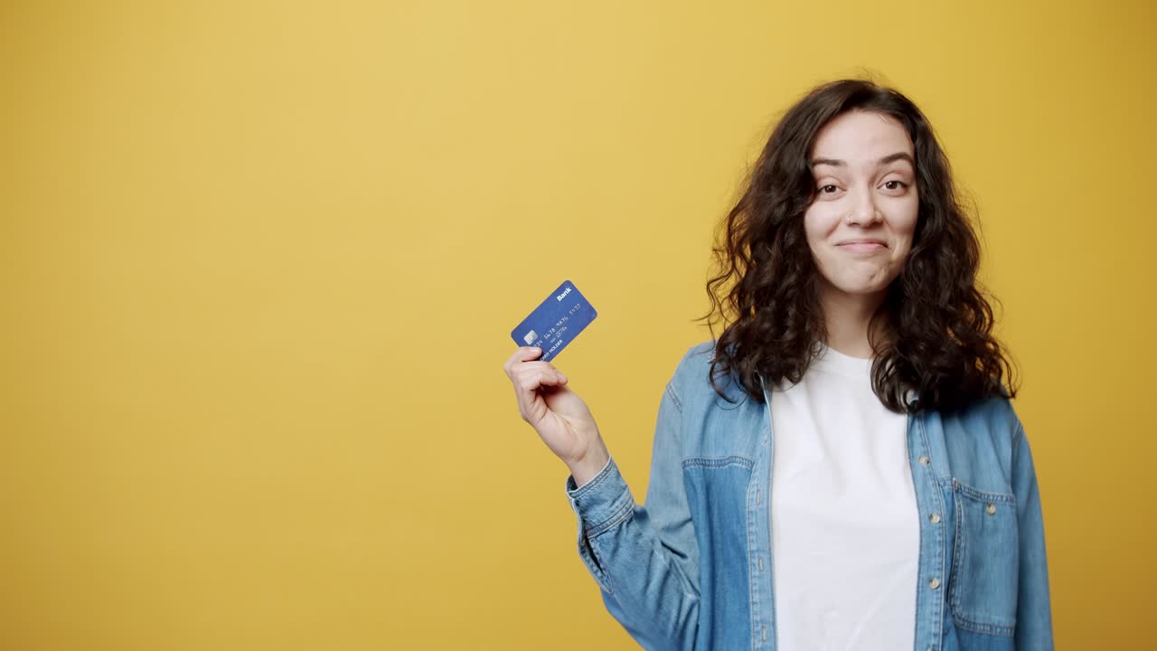 feliz mujer sonriente posando con una tarjeta de crédito en la mano, filmada en el estudio