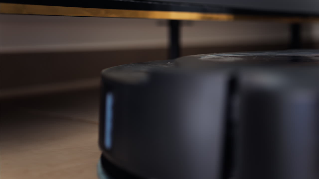 Close up of a black robot vacuum cleaner moving and rotating on the floor tiles