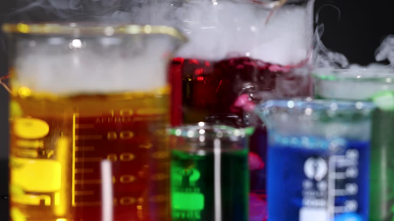 다채로운 액체와 증발하는 연기가 있는 컵