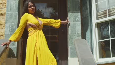 una mujer con un fluido vestido amarillo caminando bajo los arcos de un exquisito castillo.