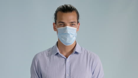 front view shot of young man putting on hygienic mask