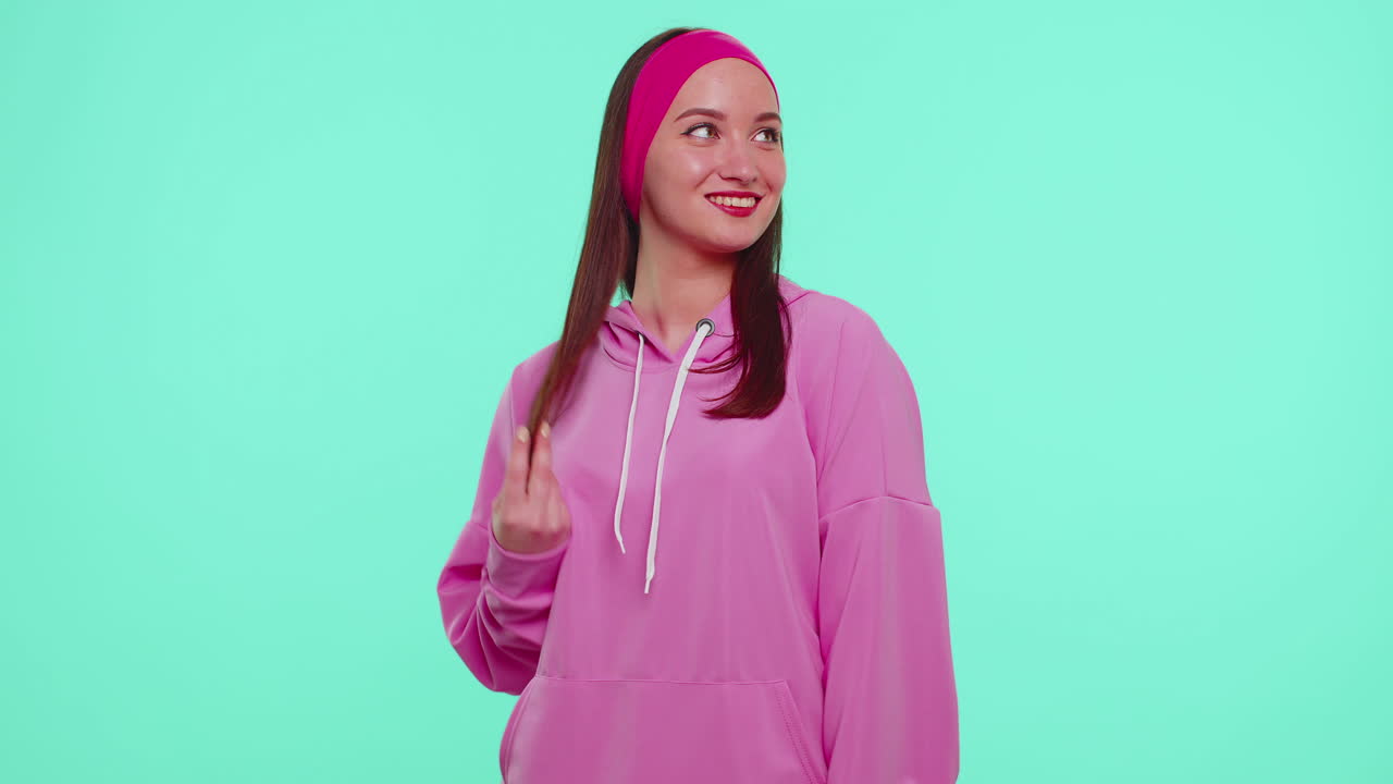 ピンクのフーディを着て笑顔でカメラを見ている陽気で可愛いティーンエイジャーの女子学生のファッションモデル