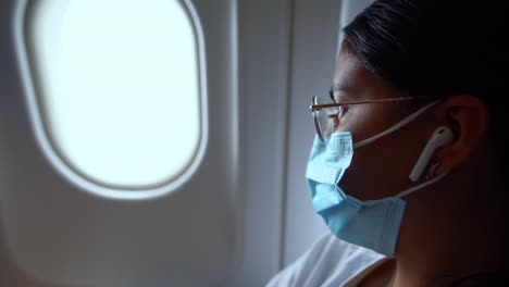 Close-up-shot-of-a-young-female-traveler-looking-through-airplane-window-during-her-long-flight