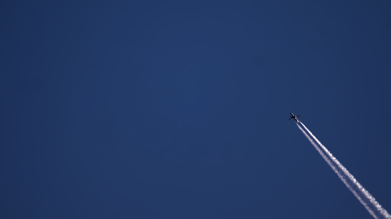 Aereo di linea che vola alto in un cielo blu limpido, lasciandosi dietro una lunga scia bianca di vapore