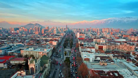 aerial view establishing of santiago de chile avenue alameda de las delicias, andes mountain range in the background at sunset, island hills