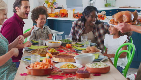 grandfather serving as multi-generation family celebrating thanksgiving at home eating meal together