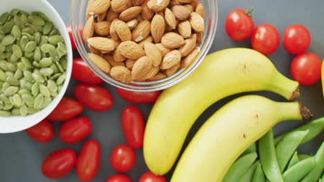 Video-of-fresh-fruit-and-vegetables-and-bowls-of-nuts-and-seeds-over-grey-background