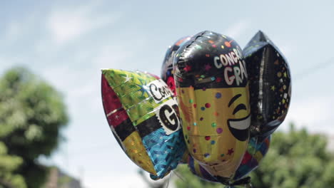 graduation balloons float in the air for celebration, slow motion, blue sky