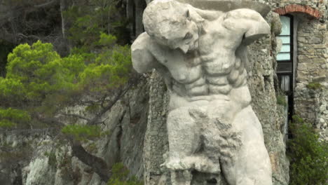 Il-Gigante-statue,-also-known-as-Monterosso-Giant,-in-Monterosso-al-Mare,-Italy-with-drone-video-close-up-parallax-in-a-circle