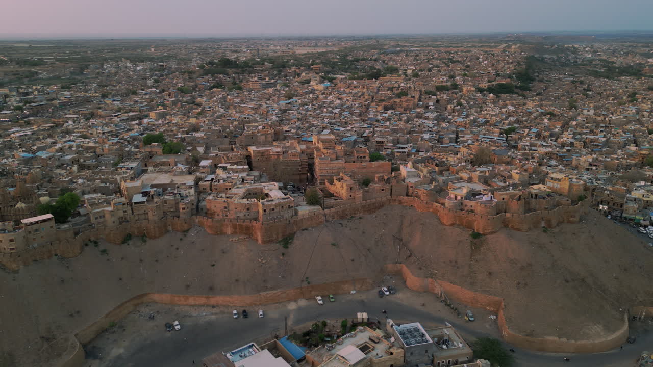 tomada de órbita del fuerte de jaisalmer al atardecer, rodeado de casas y carreteras rajasthan india 4k
