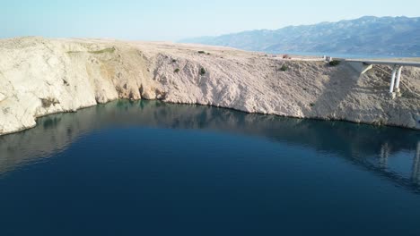 an aerial over connecting bridge to island pag and view over mountain range velebit in summer morning