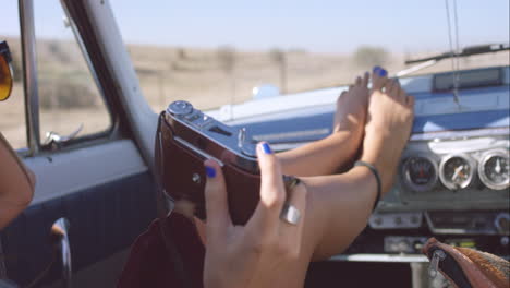 hermosa chica tomando fotos con una cámara vintage en un viaje por carretera en un coche convertible