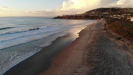 A-drone-flies-down-the-coast-revealing-a-stunning-sunset-at-the-beach