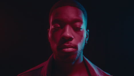 handsome black man posing in dark studio with neon lights