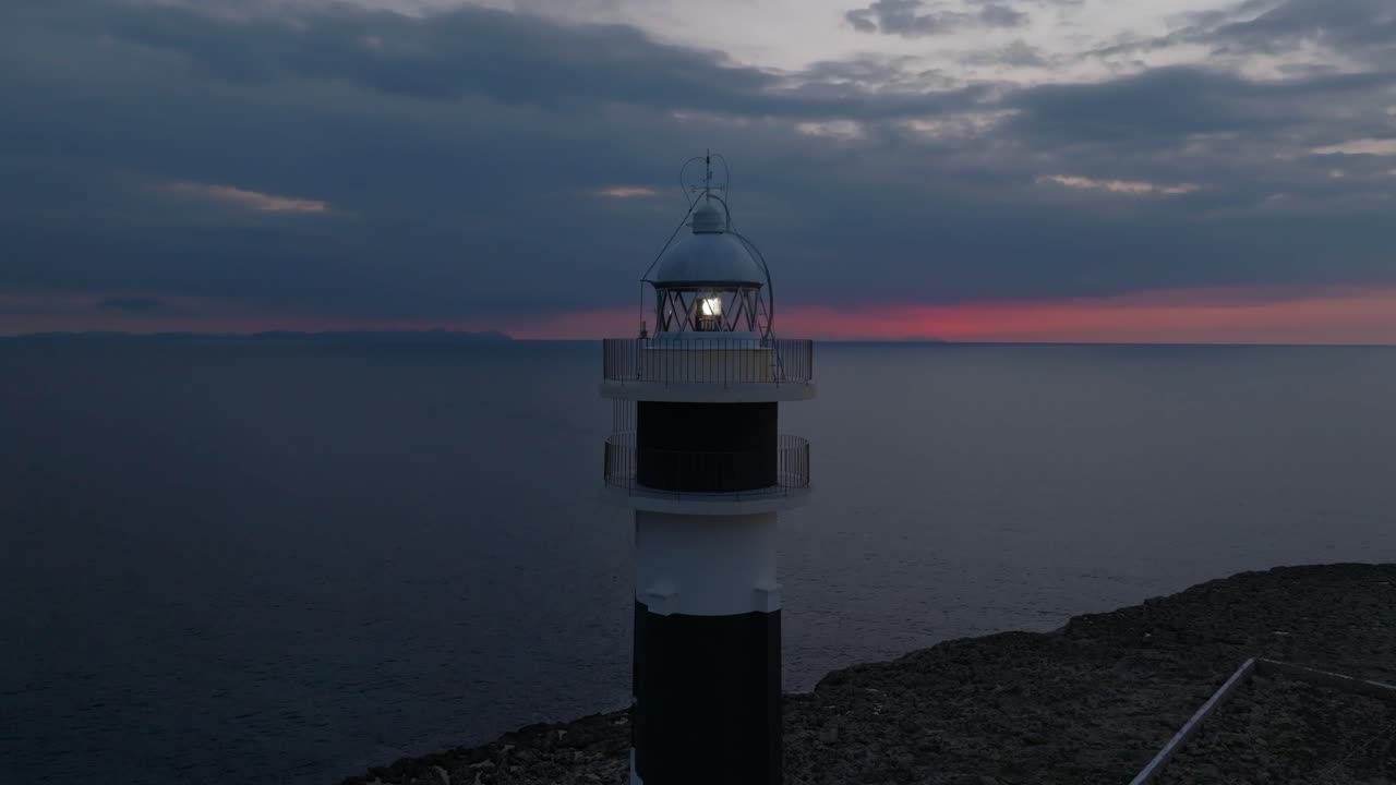 Aerial close up view of Cap d’Artrutx Lighthouse with Fiery Sunset Sky, drone orbit