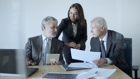 mature male executives and cheerful female assistant in a meeting