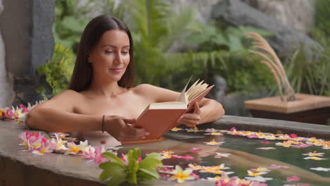 woman relaxing in a flower bath and reading a book
