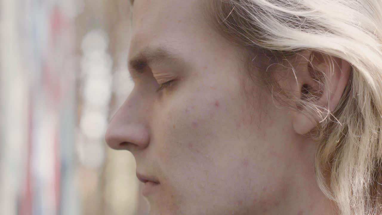 Close-up profile view of a young man in a forest