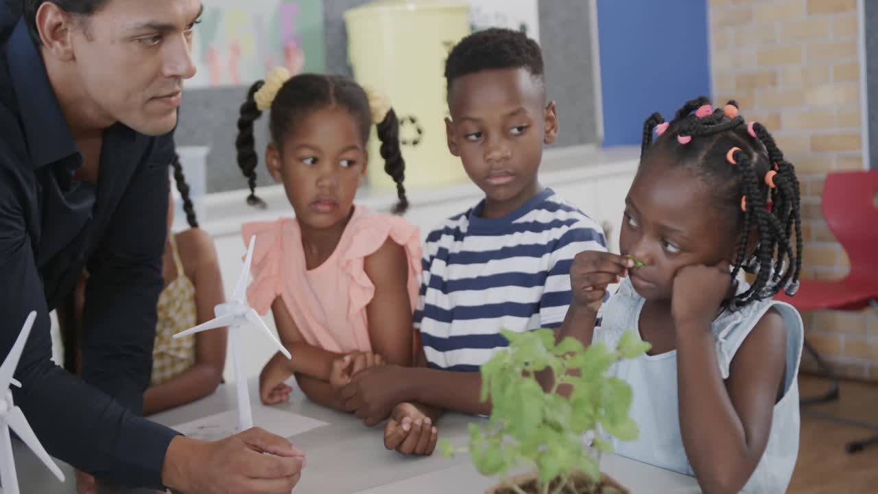 Diverse male teacher and children studying plants in elementary school ecology class, slow motion