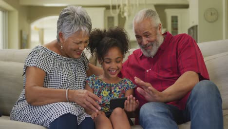 abuelos y nieta usando teléfonos inteligentes en casa