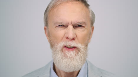 serious man squinting eyes in studio. senior gentleman looking camera indoors.