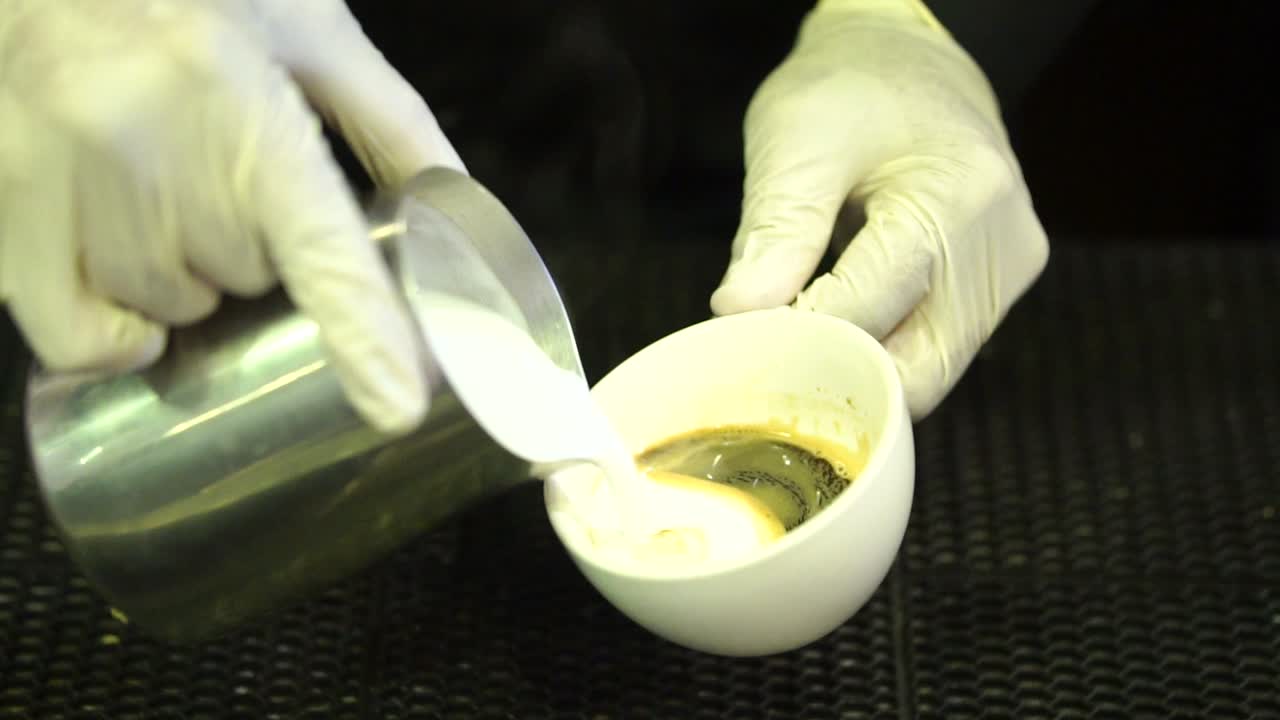 Pouring hot milk over espresso shot of coffee making a latte