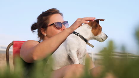 Attraktive-Kaukasische-Frau-Streichelt-Süßen-Aufmerksamen-Jack-Russell-Terrier-Auf-Ihrem-Schoß